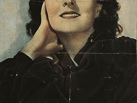 Porträt einer lächelnden Frau. Ihr Kopf ist auf den Arm gestützt.