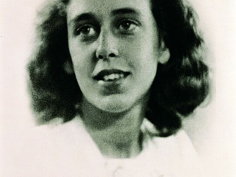 Studio-Porträt: Eine junge Person mit schulterlangem, lockigem Haar.