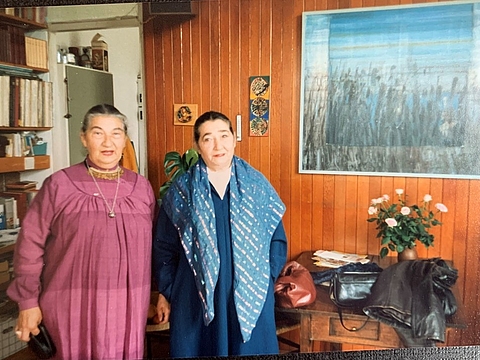 Zwei ältere Frauen nebeneinander in einem Wohnraum.