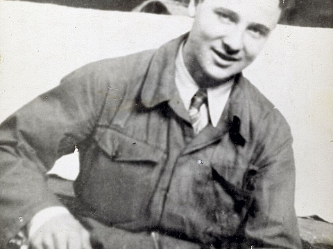 Eine jugendliche Person mit einem Werkzeug in der Hand blickt lächelnd in die Kamera.