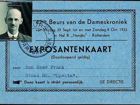 Ein Foto von einer blauen Karte mit Schriftzug. In der Mitte der Karte ist ein Stempel. Links oben in der Ecke ist ein Passfoto von einem Mann getackert.