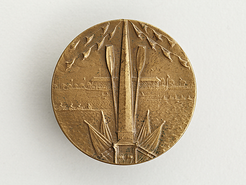 Ein Foto von einer runden, goldfarbenen Medaille mit einem geprägten Rudermotiv.