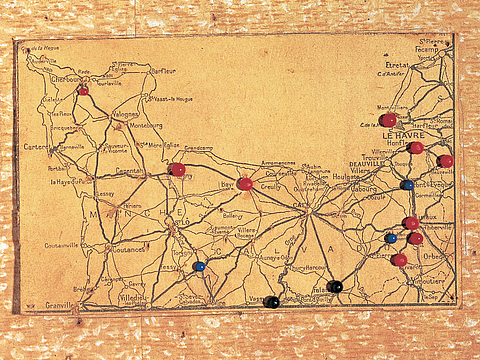 Ein Foto von einer Landkarte mit Ortsbeschriftungen. Auf der Karte sind verschiedene bunte Nadeln an bestimmten Orten eingesteckt.