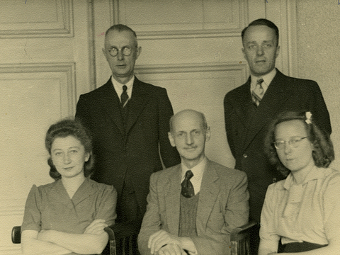 Ein Foto von fünf Erwachsenen, die in die Kamera schauen. Ein Mann sitzt in der Mitte von zwei Frauen in der ersten Reihe und hinter diesen stehen zwei Männer. 